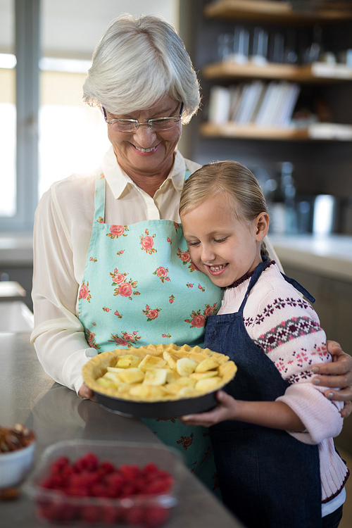 Grandmother and granddaughter looking at fresh cut apples on crust while making apple pie