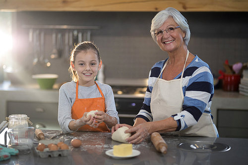 Grandmother and granddaughter kneading dough in the kitchen