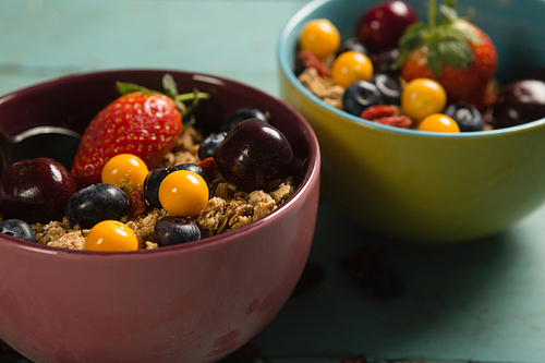 Bowls of breakfast cereals and fruits on wooden table