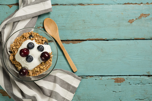Bowls of breakfast cereals and fruits with yogurt on wooden table