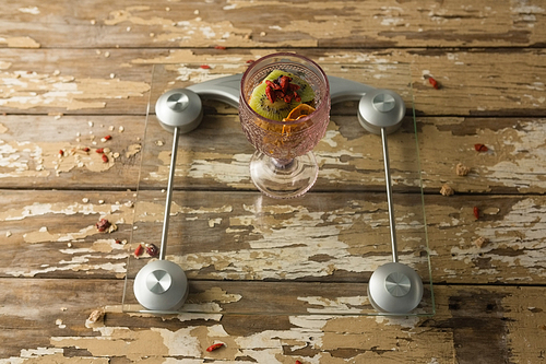 Glass of breakfast on weighing scale on wooden table