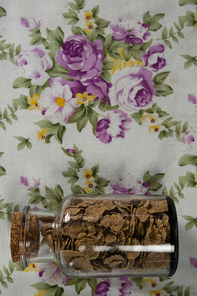 Wheat flakes in glass jar on floral background