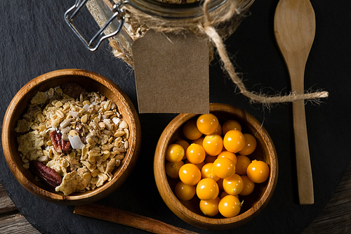 Bowl of cape gooseberry and muesli on wooden board