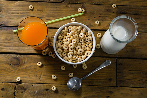 Close-up of cereal rings, orange juice and milk on wooden table