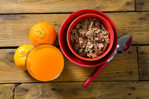 Close-up of wheat flakes and orange juice on wooden table