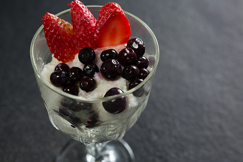 Glass of yogurt, black cherries and strawberries for breakfast on table