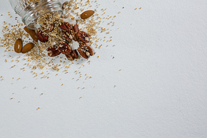 Dried fruits spilling out of bottle on white background