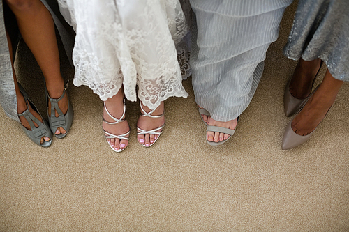 Low section of bride and bridesmaids standing at home