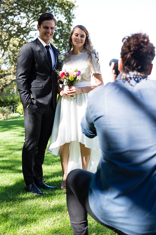 Photographer taking photo of newly married couple in park
