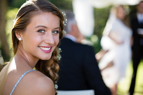 Portrait of beautiful bridesmaid smiling in park during wedding