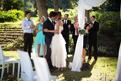 Affectionate couple kissing each other in park during wedding