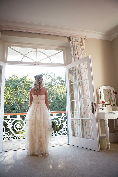 Rear view of bride in dress standing at doorway at home