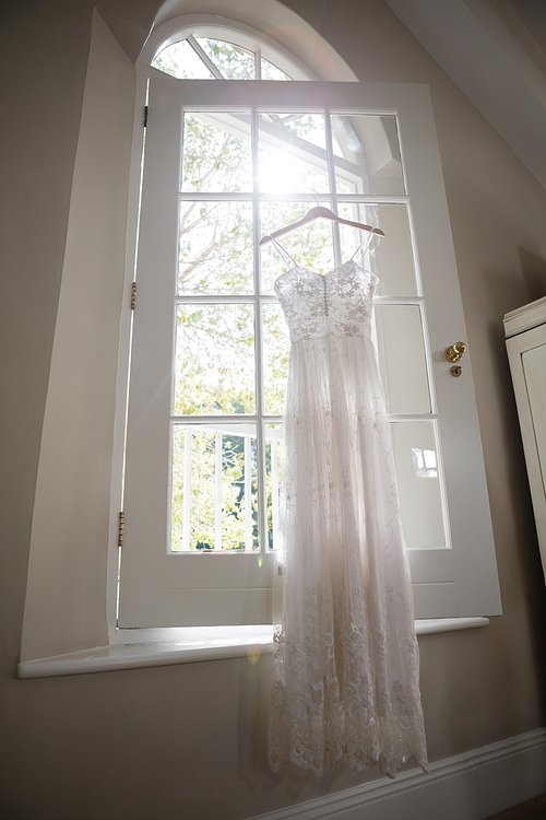 Wedding dress hanging on window in dressing room