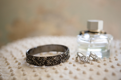 Close up of earring with bangle and perfume bottle in dressing room