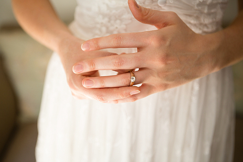 Midsection of bride wearing wedding ring while standing at home