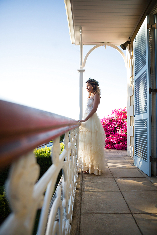 Side view of beautiful bride standing by railing in balcony