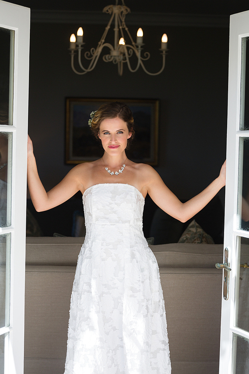 Portrait of smiling beautiful bride standing at doorway