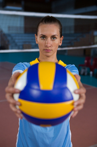 Portrait of young female sportsperson holding volleyball at court