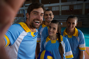 Portrait of happy volleyball players standing at court