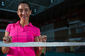 Portrait of smiling female volleyball player standing behind net
