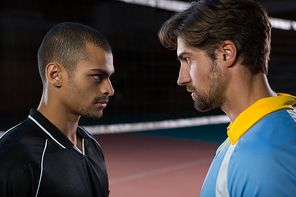 Aggressive male volleyball players looking each other at court