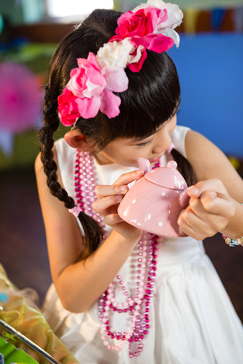 Close-up of cute girl holding toy teapot during birthday party at home