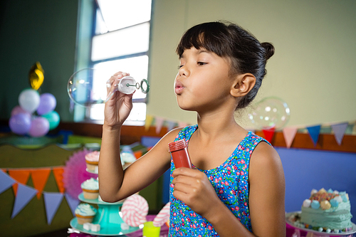 Girl playing with bubble wand during birthday party at home