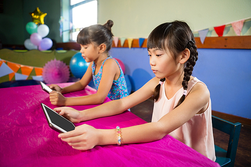 Little girls using tablet at party at home