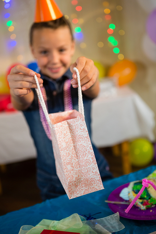 Girl holding a gift bag during birthday party at home