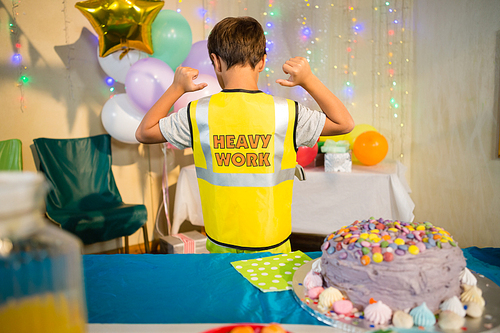 Rear view of boy gesturing to the text on protective workwear