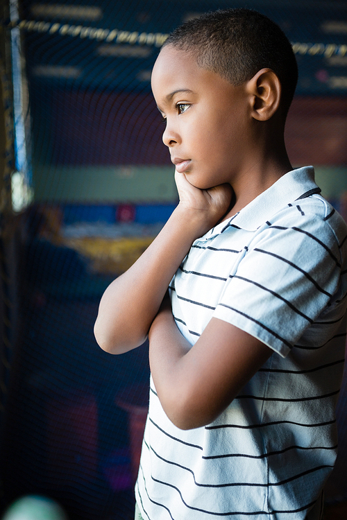 Thoughtful boy standing near window at home