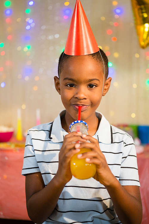 Portrait of happy boy drinking juice during birthday party at home