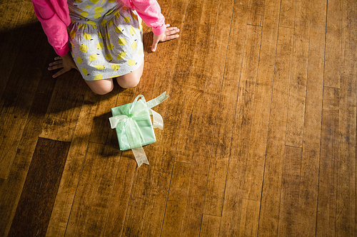 Girl sitting with gift box on wooden floor at home