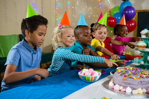 Kids pointing on cake at table during birthday party