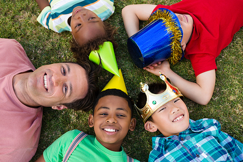 Overhead view of man with children lying on field during party