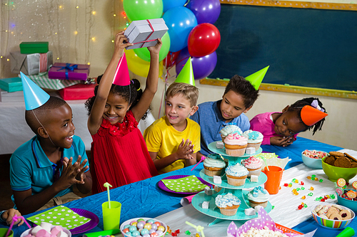 Cheerful children sitting at table during birthday party