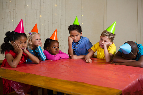 Tired children sitting at table during birthday party