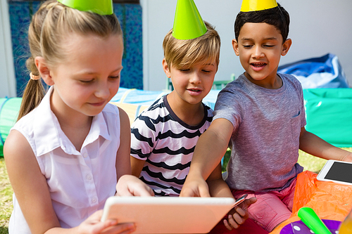 Children using digital tablet during birthday party in yard
