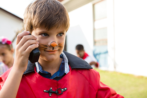 Boy with face paint using walkie talkie while looking away during birthday party in yard