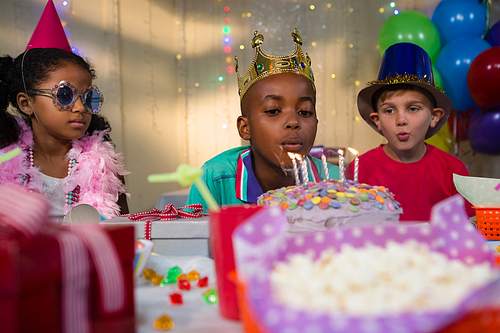 Boy blowing candles on birthday cake during party