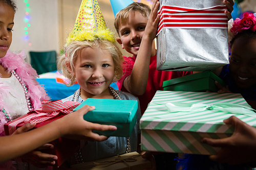 Portrait of smiling girl receiving gifts from friends during birthday
