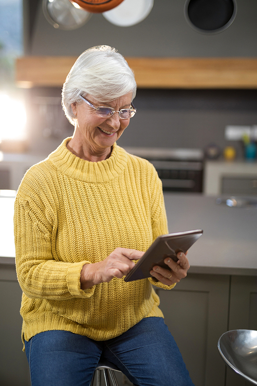 Smiling senior woman using digital tablet in kitchen at home