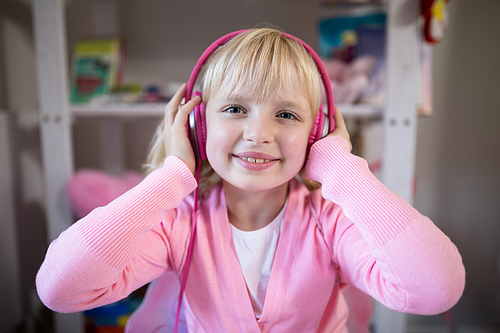 Smiling cute girl listening to pink headphones