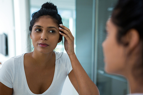 Woman reflecting on mirror in bathroom at home