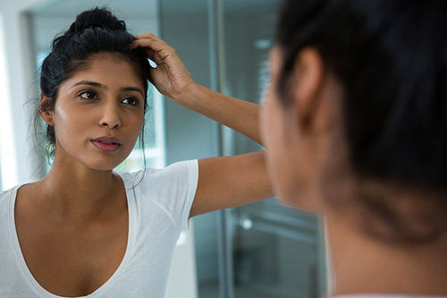 Pretty woman reflecting on mirror in bathroom at home