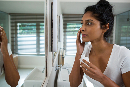 Woman applying lotion in bathroom at home