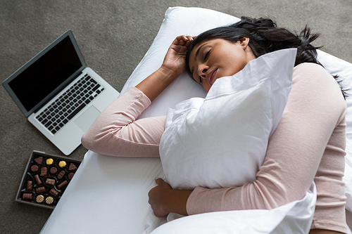 Young woman sleeping on bed over floor at home