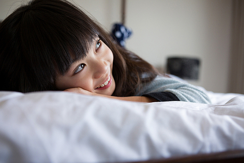 Smiling girl relaxing on bed at home