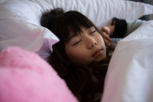 Girl with pink toy sleeping on bed at home
