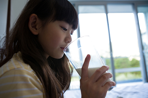 Girl drinking milk on bed at home